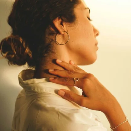 a woman wearing a white shirt and gold hoop earrings