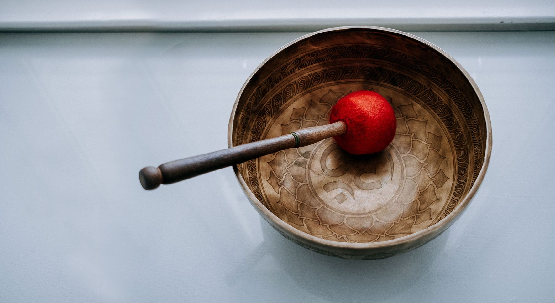 Tibetan singing bowl with wooden mallet with a red ending.