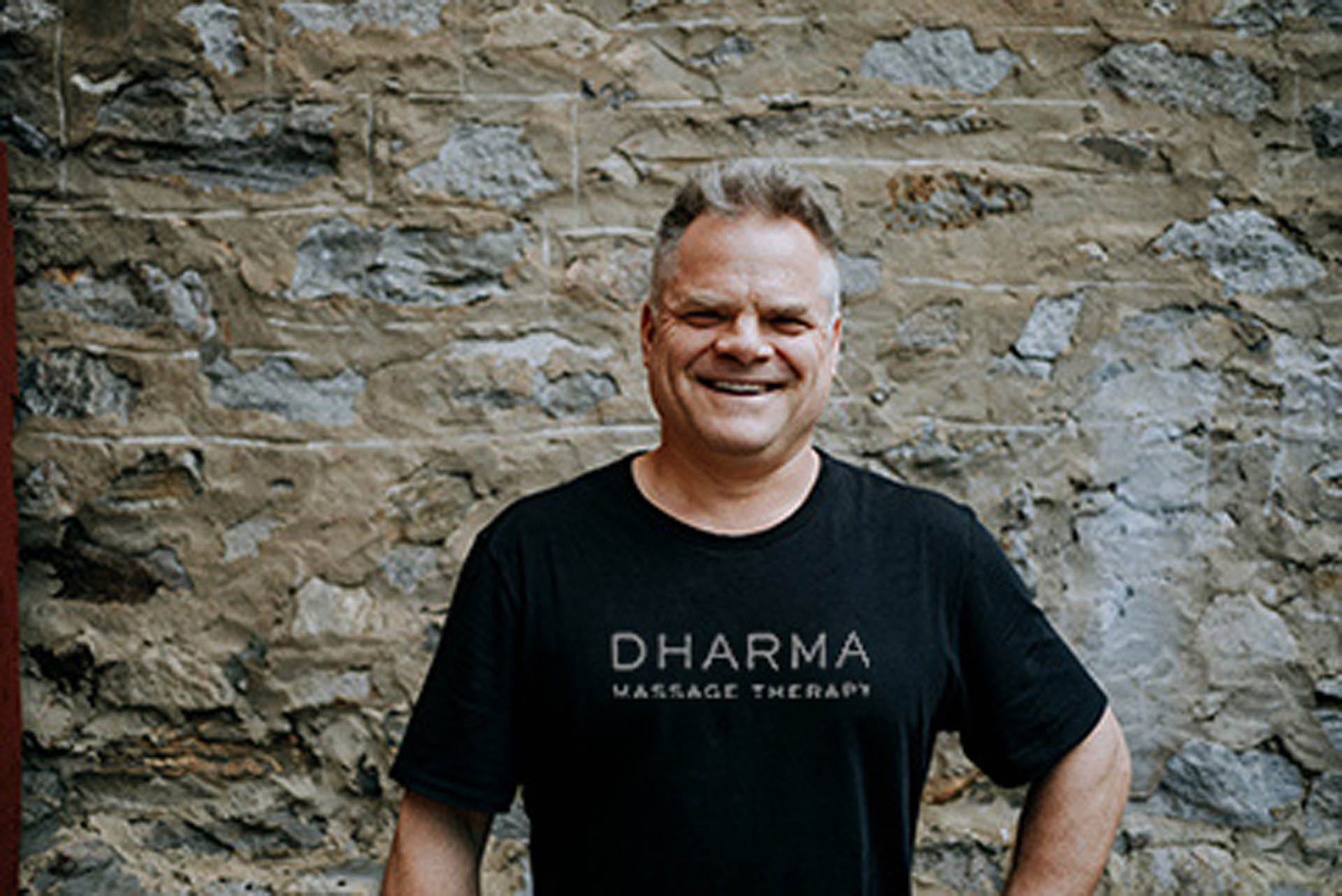 Massage therapist Mark standing in Dharma Massage shirt