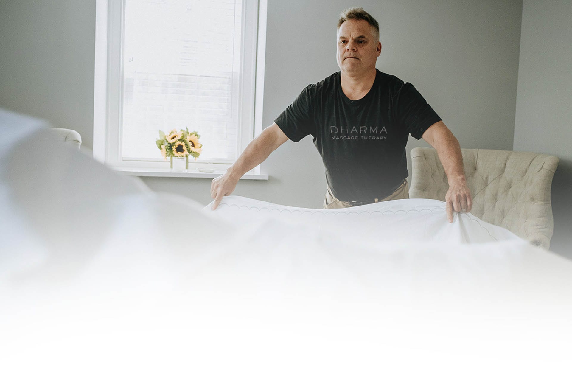 Massage therapist setting up massage table with clean sheets