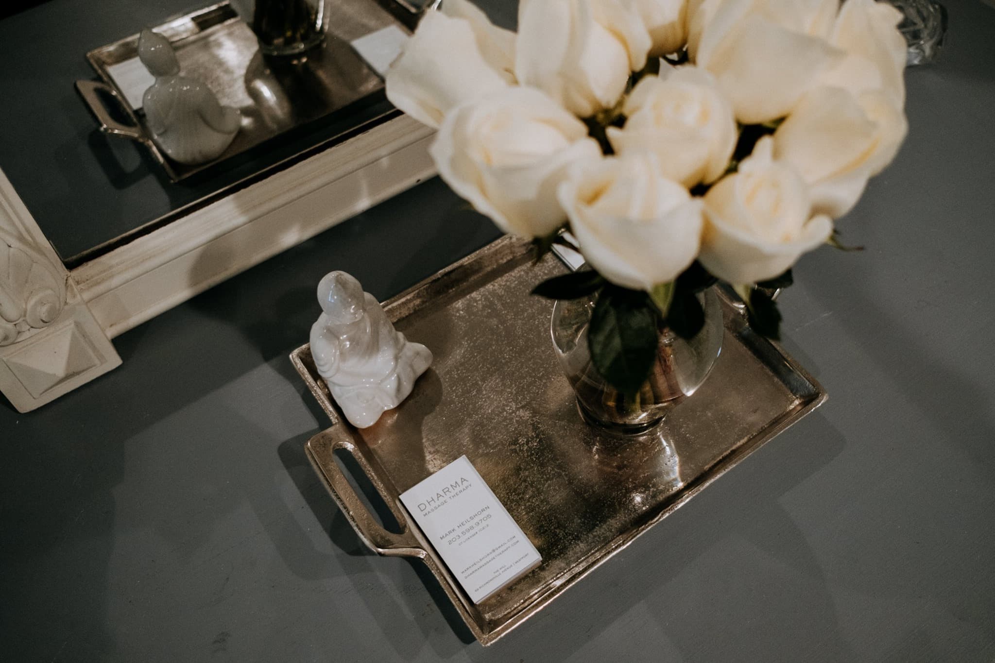 spa tray with white flowers in vase, white small buddha statue and notepad